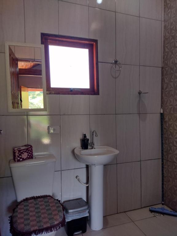 ブエノ・ブランダンにあるChalés Encantos de Minasのバスルーム(洗面台、トイレ付)、窓が備わります。