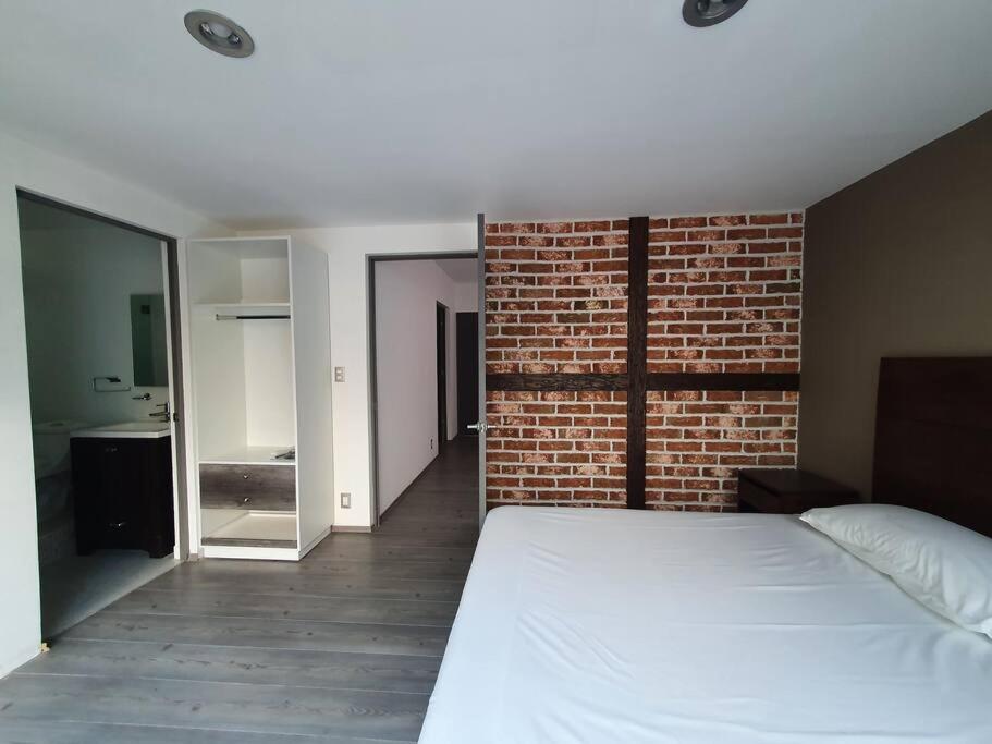 1 dormitorio con cama blanca y pared de ladrillo en Hermosa casa ideal familias o grupos grandes, en Ciudad de México