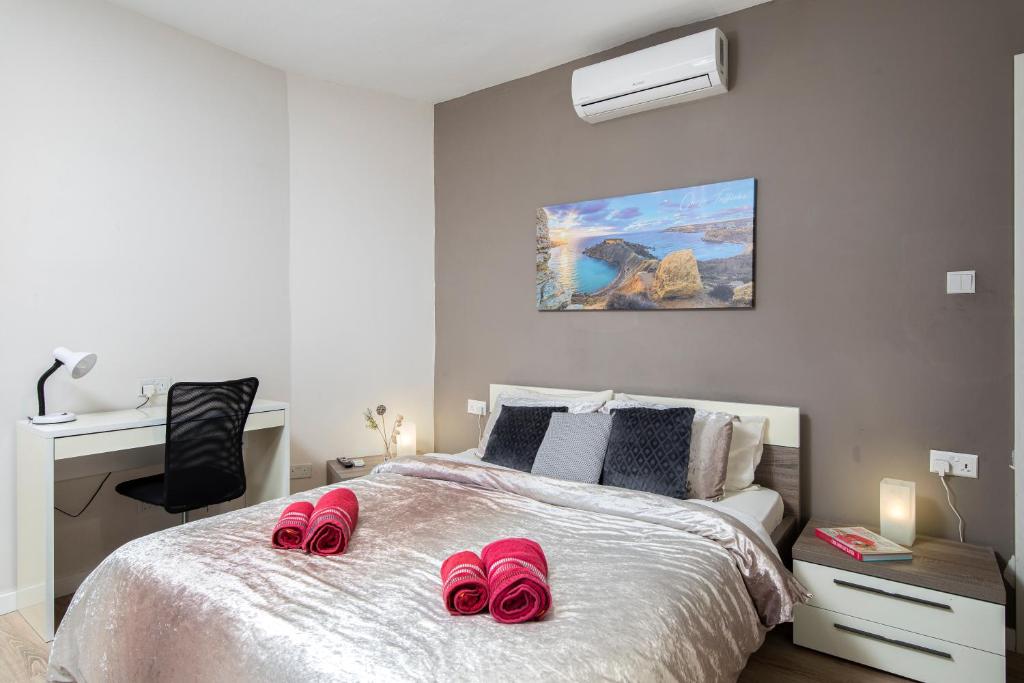 een slaapkamer met een bed met roze slippers erop bij Luxury Msida Circle Suites in Msida