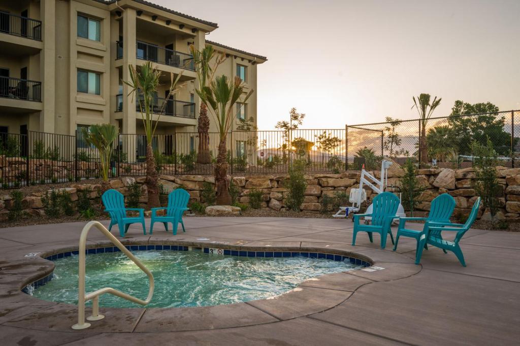 a pool with chairs and a table and a building at S404-The Penthouse-Fourth Floor 3-bedroom Pool View in St. George