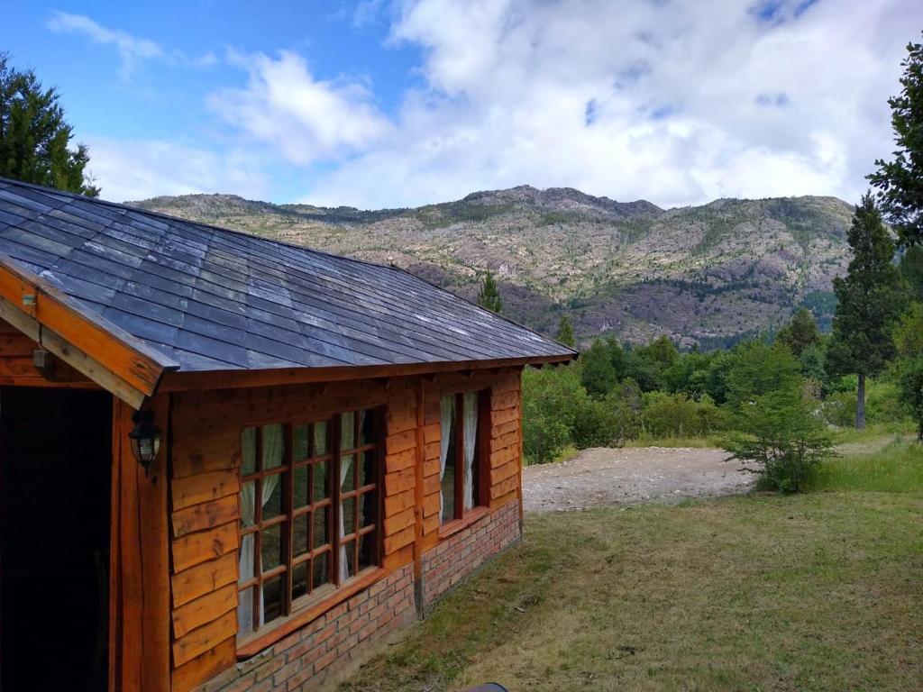un piccolo edificio con tetto con montagne sullo sfondo di Cabaña El Sueño de La Abuela a El Hoyo