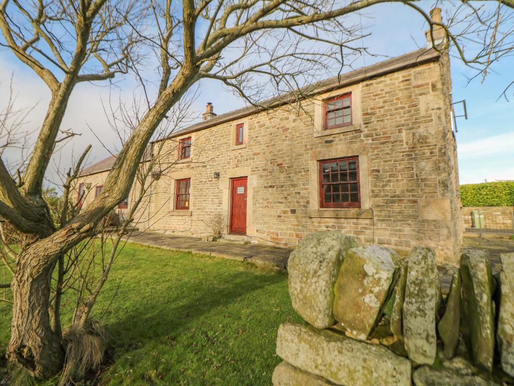 an old stone house with a red door at The Old Robin Hood in Holmesfield