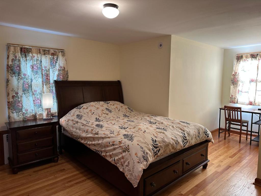 a bedroom with a bed and a table and two windows at J1 Pleasant Room near Rutgers U, hospitals in New Brunswick