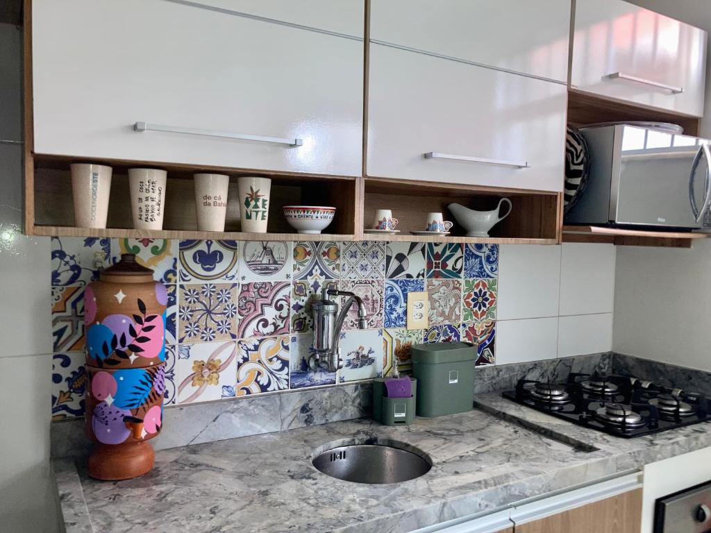 a kitchen with a sink and a tile wall at Apartamento Oxe! Tô na Bahia in Salvador