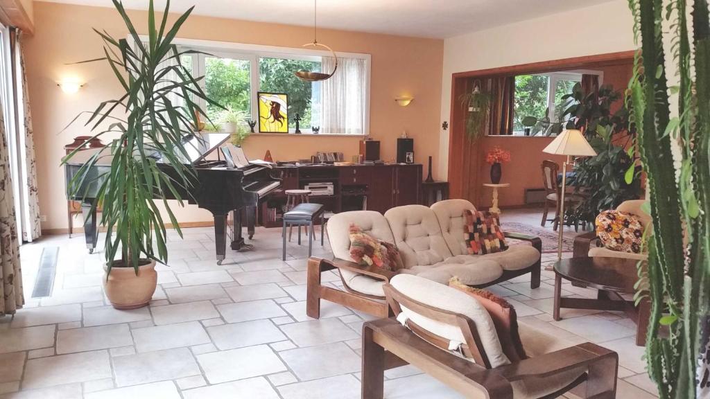 una sala de estar con muebles y un piano de cola. en Prince d'Orange Bed & Breakfast en Braine-lʼAlleud