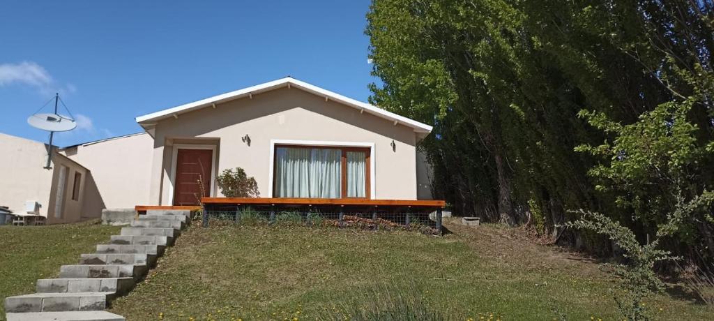 una pequeña casa blanca al lado de un patio en Casa de la Loma en El Calafate