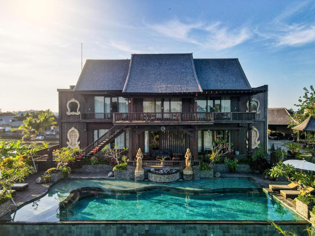 a large house with a swimming pool in front of it at Royal Roco Villa in Tanah Lot