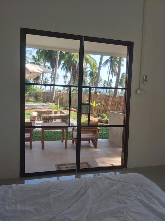 een slaapkamer met een groot glazen raam met uitzicht op een patio bij Nice Home Stay @Samroiyot in Sam Roi Yot
