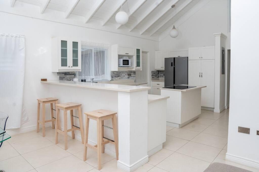 una cocina blanca con encimera y taburetes en House Of The Sun Vacation Home No 1, en Brissett Run