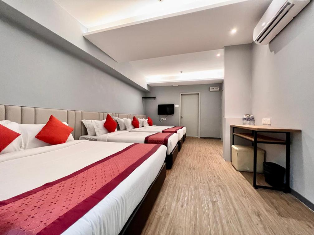 a hotel room with three beds and a television at Bayu 23 Hotel in Kota Kinabalu