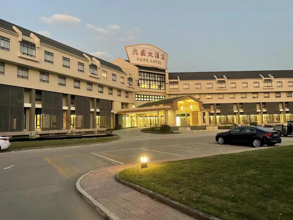 a large building with a car parked in a parking lot at 无锡花园大酒店 in Wuxi