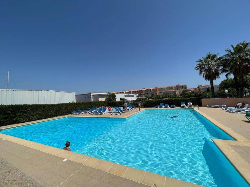 una gran piscina azul con sillas y palmeras en Studio Cap d'Agde, 1 pièce, 4 personnes - FR-1-702-2, en Cap d'Agde