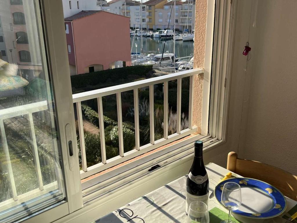 butelka wina na stole obok okna w obiekcie T2 avec ascenseur, parking proche plage - FR-1-702-21 w Cap d'Agde