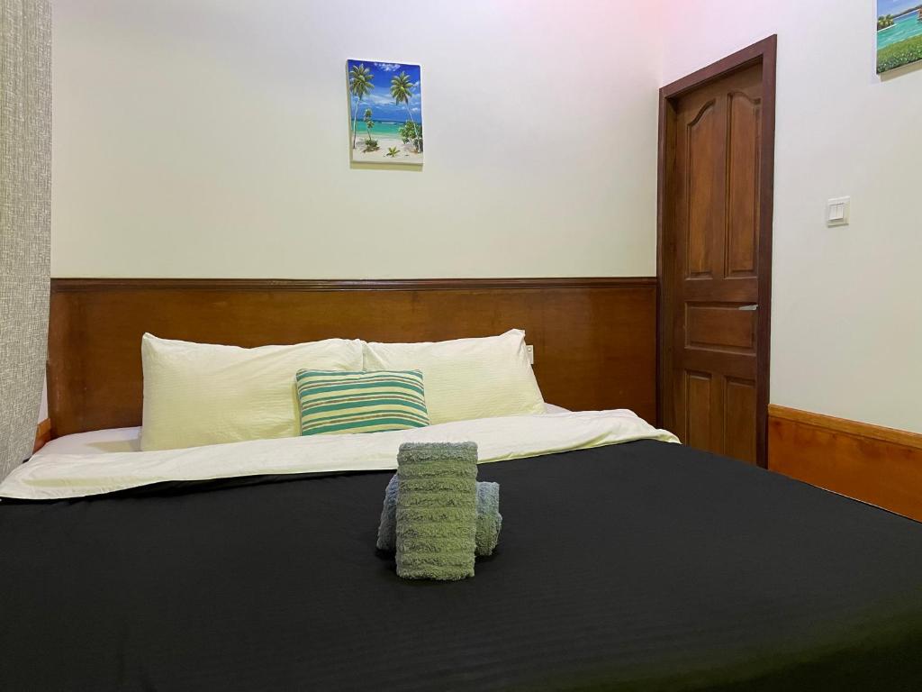 Una cama con cabecero de madera y un taburete verde. en LETS GO HURAA, en Huraa