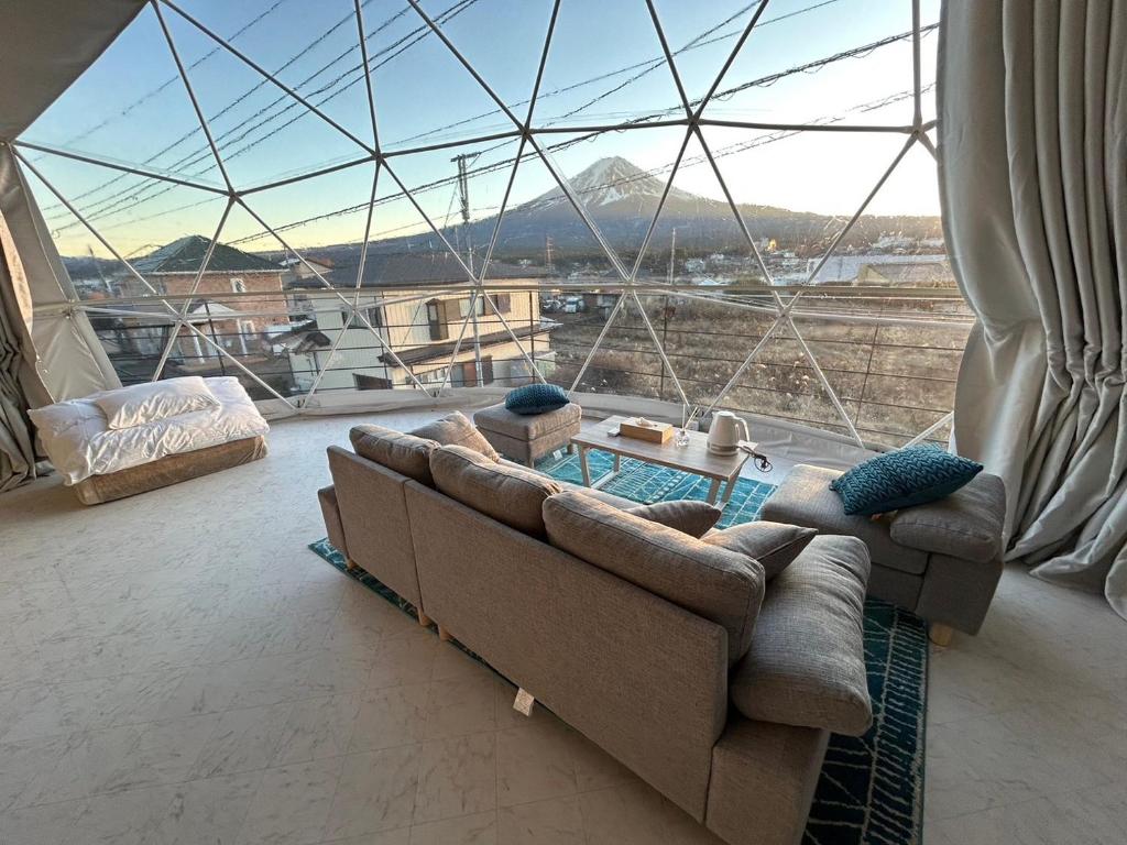 a living room with a couch and a large window at Glamping Dome YOSHIMURA in Fujikawaguchiko