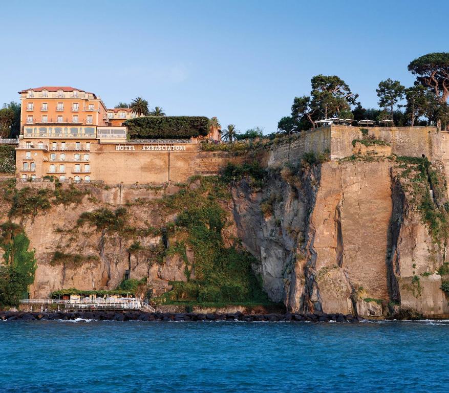a building on a cliff next to the water at Grand Hotel Ambasciatori in Sorrento