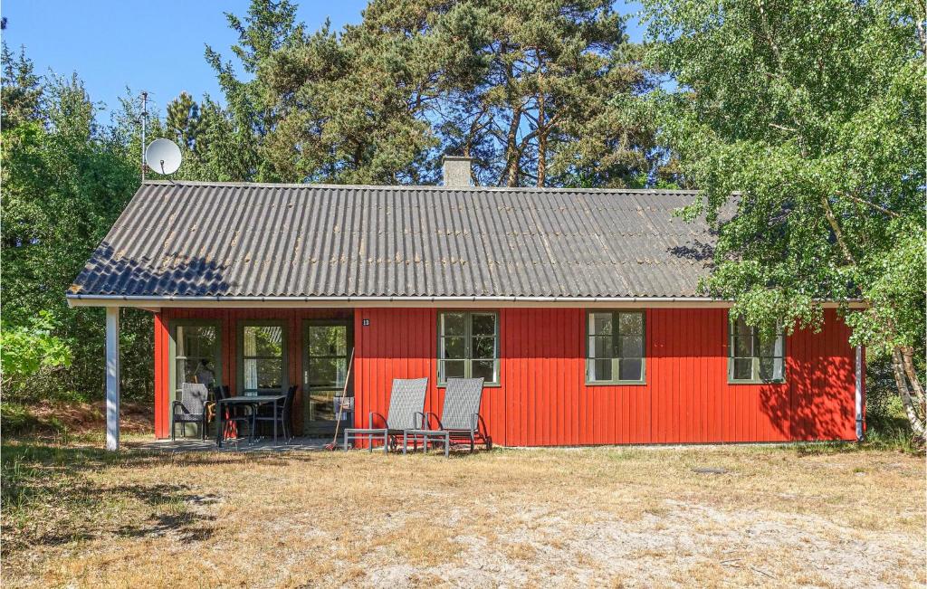 a red house with two chairs and a table at 3 Bedroom Gorgeous Home In Aakirkeby in Vester Sømarken