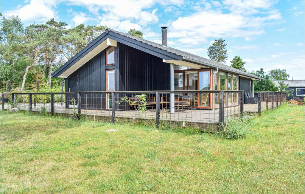 Ein schwarzes Haus mit einem Zaun auf einem Feld in der Unterkunft Stunning Home In Grsted With Wifi in Græsted