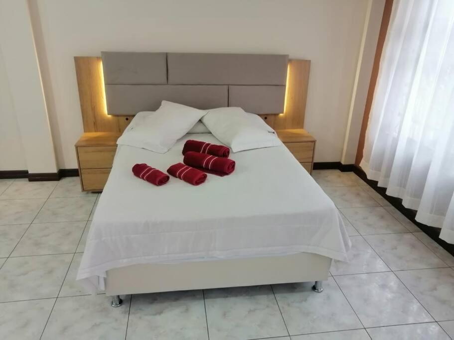 a white bed with two red pillows on it at Belle Ville Tarapaca in Sucre