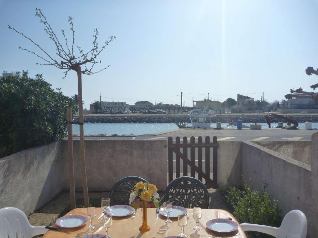 - une table avec des chaises et des verres à vin sur la terrasse dans l'établissement Maison climatisée avec parking et terrasses, 2 chambres, quartier calme - FR-1-387-68, à Marseillan