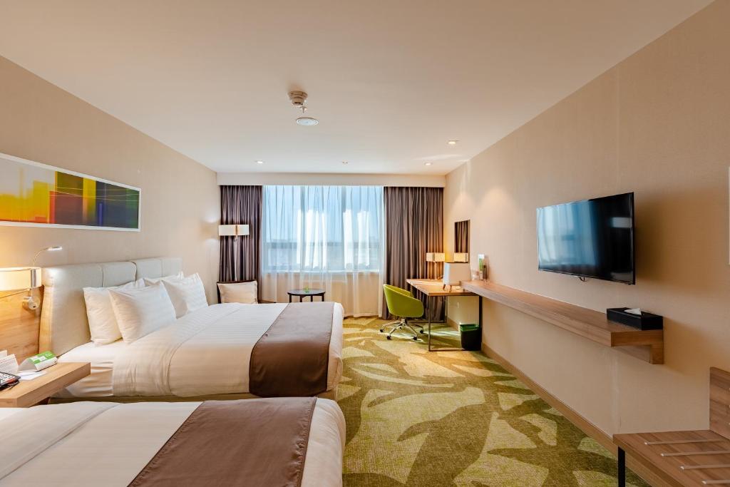 ein Hotelzimmer mit 2 Betten und einem Flachbild-TV in der Unterkunft Holiday Inn Ulaanbaatar, an IHG Hotel in Ulaanbaatar