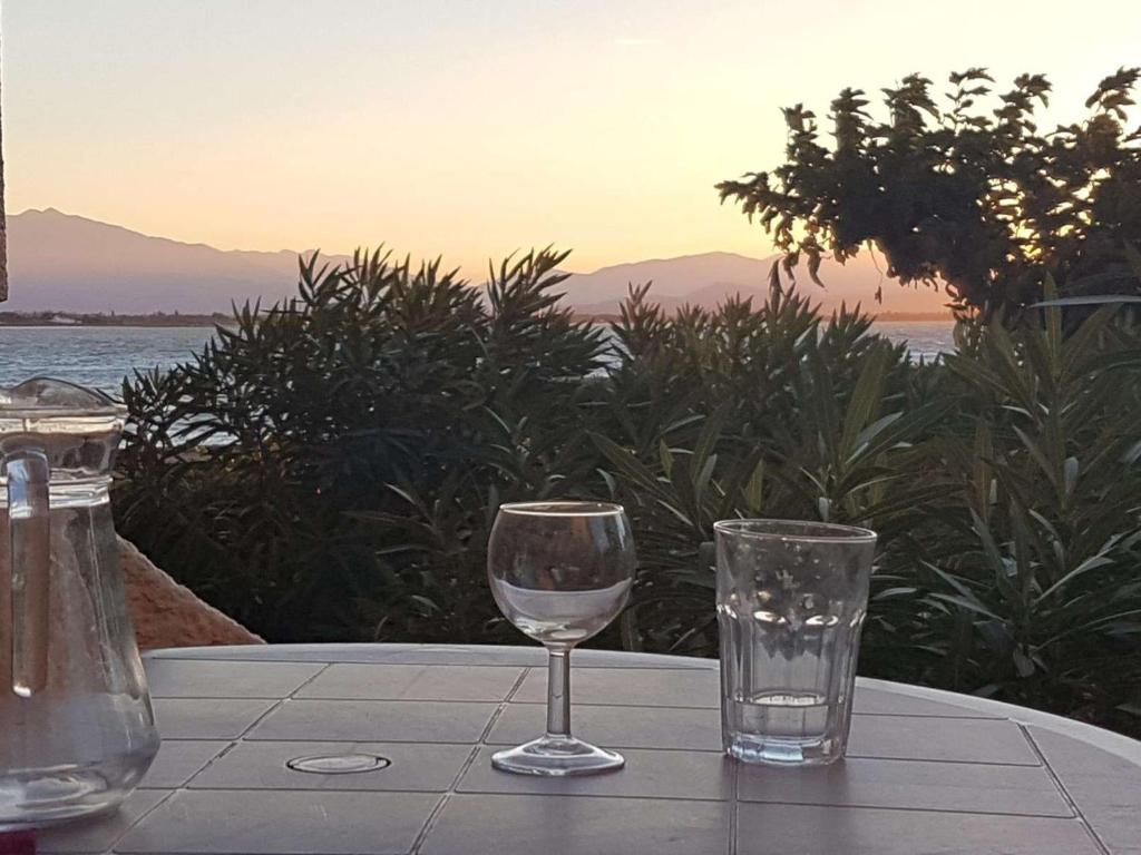 - une table avec deux verres sur une table avec vue sur l'océan dans l'établissement T2 calme avec terrasse et accès à la piscine au bord du lac - FR-1-195-77, au Barcarès