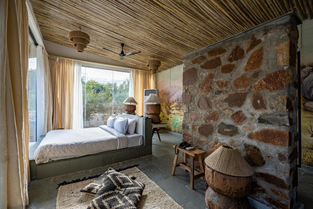 1 dormitorio con cama y pared de piedra en Utsav Camp Sariska en Tehla