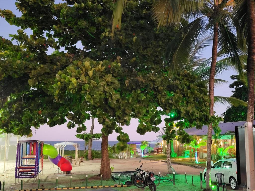 a tree with a playground and a motorcycle parked under it at Boa Beach House in Porto Seguro