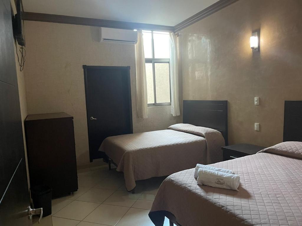 Habitación de hotel con 2 camas y ventana en Hotel San Salvador, en San Juan de los Lagos