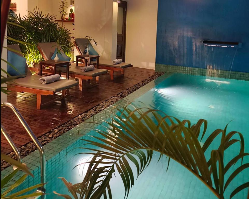 a pool with lounge chairs next to a swimming pool at Baahu Villa in Siem Reap