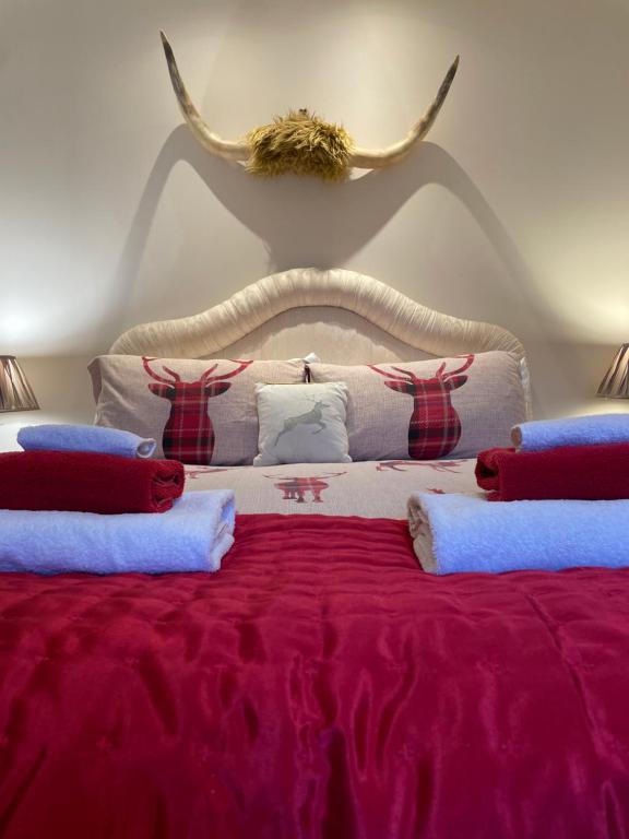 a bedroom with a bed with red sheets and antlers on the wall at Red Stag Apartment in Nairn