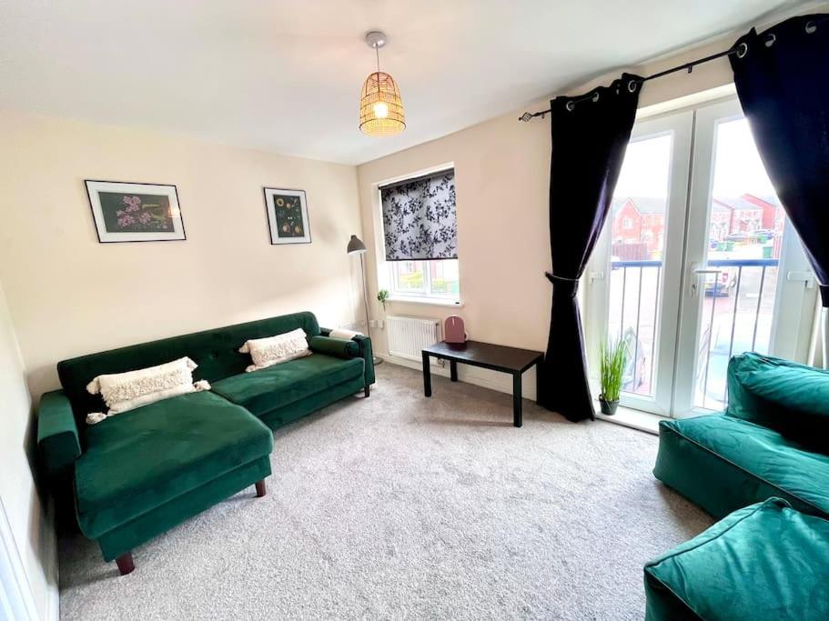 a living room with two green couches and a table at 4 bedroom house spacious free parking, #1 location in Pallion