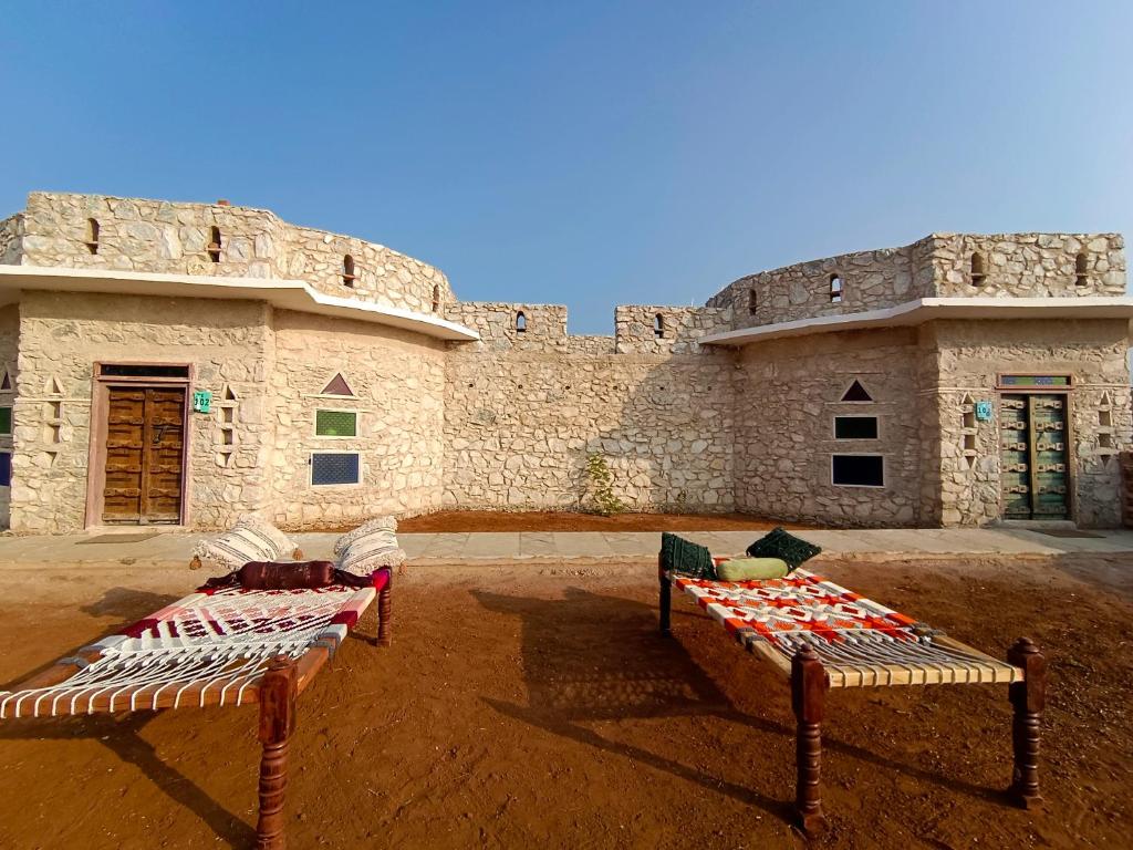 two beds sitting in front of a building at Sariska Kasba A Village Resort in Tehla