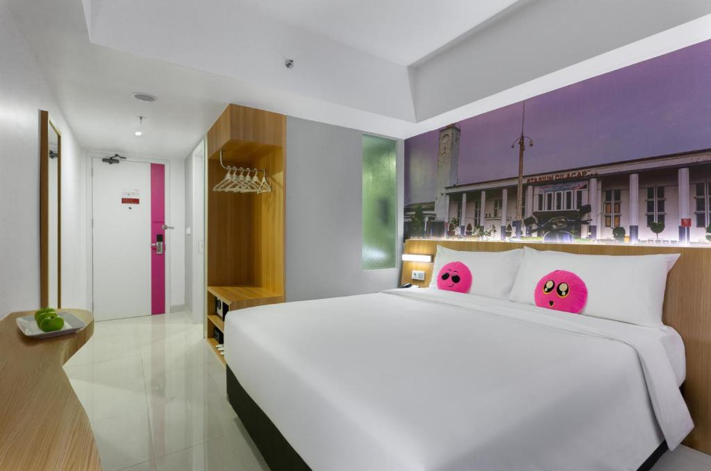 a bedroom with a white bed with hello kitty pillows at favehotel Cilacap in Cilacap