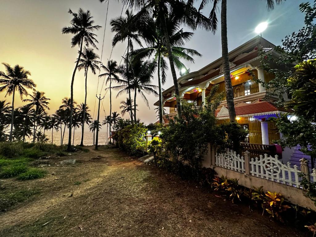 Kovalam Beach House في تريفاندروم: منزل به أشجار نخيل أمام المحيط