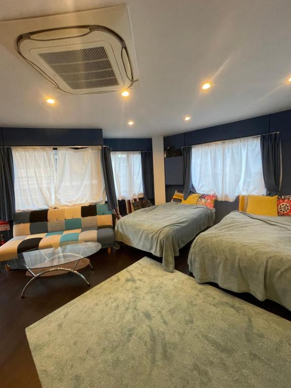 1 dormitorio con 2 camas, sofá y ventanas en spaceMU en Osaka