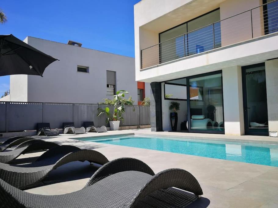 a house with a swimming pool with chairs and an umbrella at Precioso chalet vanguardista in Palma de Mallorca