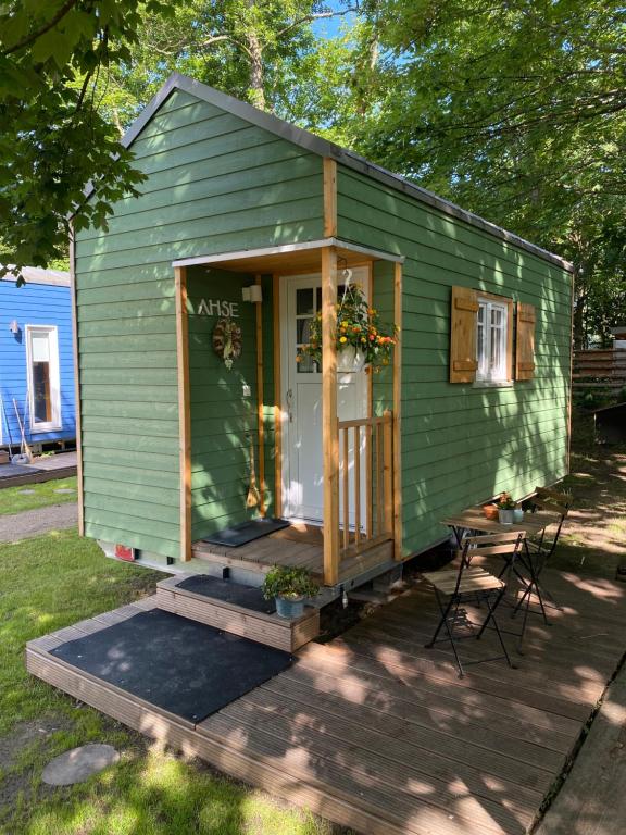 uma casa verde com uma porta, uma mesa e cadeiras em Tiny House Ahse im PIER9 Tiny House Hotel em Hamm