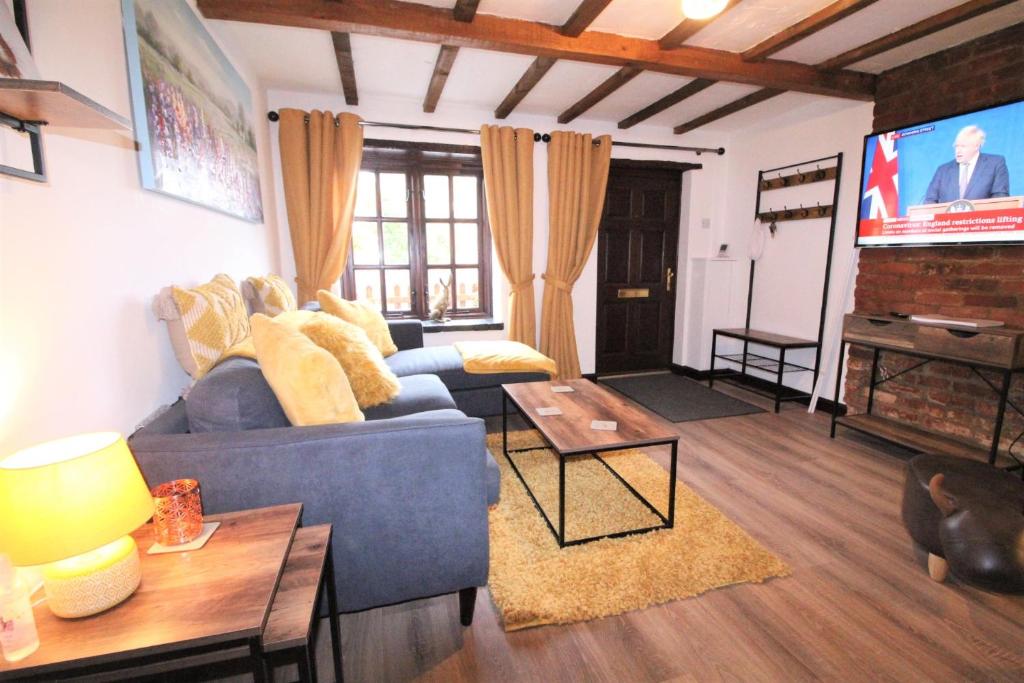 un salon avec un canapé bleu et une télévision à écran plat dans l'établissement Jasmine Cottage, Buxton Norfolk, Sleeps 4, à Norwich