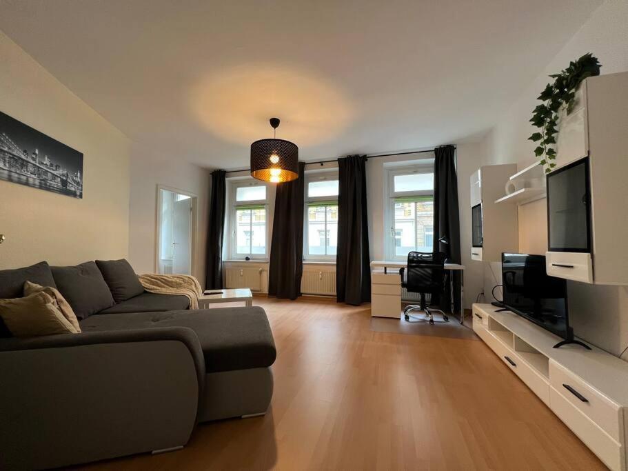 Il comprend un salon doté d'un canapé et d'une télévision à écran plat. dans l'établissement R&L Apartment Uhlandstrasse, à Leipzig