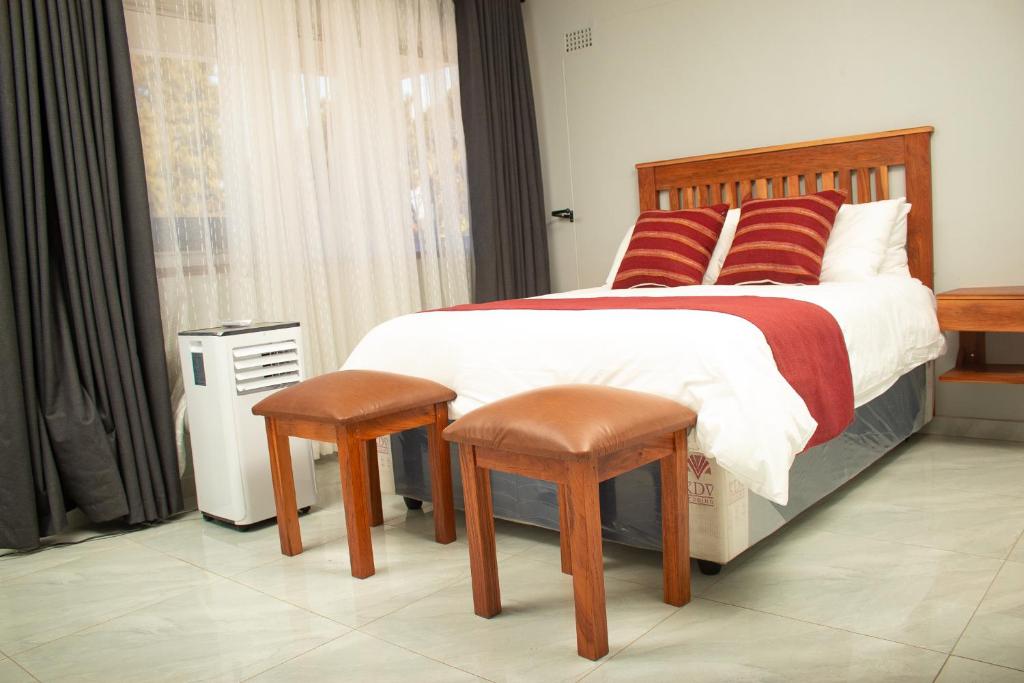 a bedroom with a large bed with two stools at R Executive Apartments in Harare