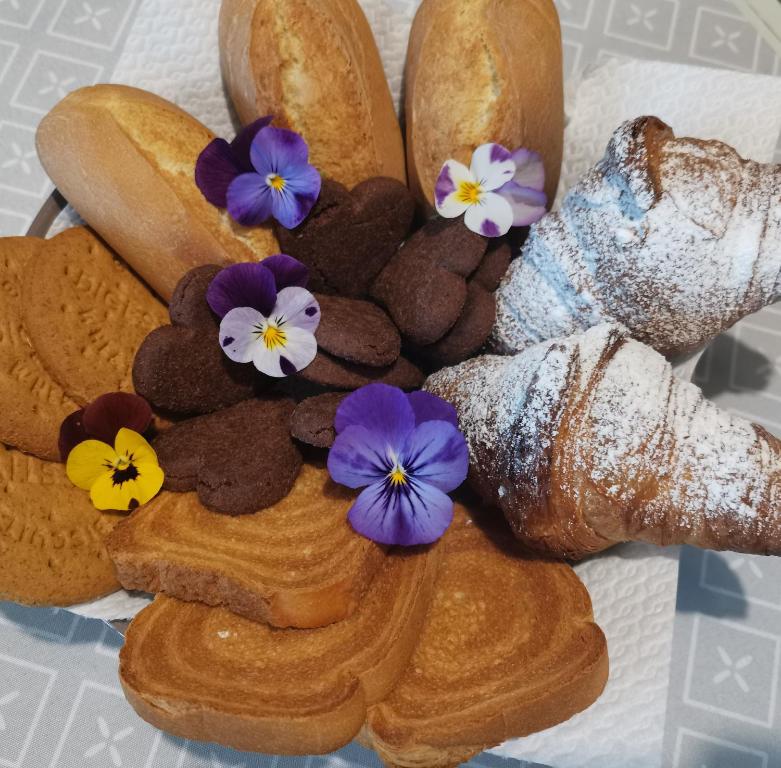 Il Colibrì Bed&Breakfast في Leno: مجموعة من أنواع الخبز مع الزهور الأرجوانية
