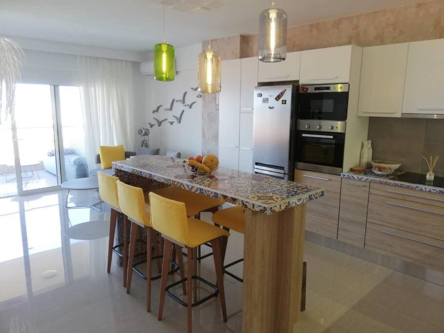 a kitchen with a counter with yellow bar chairs at W Apartment in Chania Town