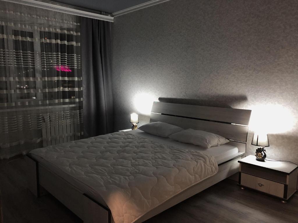 1 dormitorio con 1 cama con 2 lámparas y una ventana en Квартира в центре города посуточно, понедельно, en Kokshetau