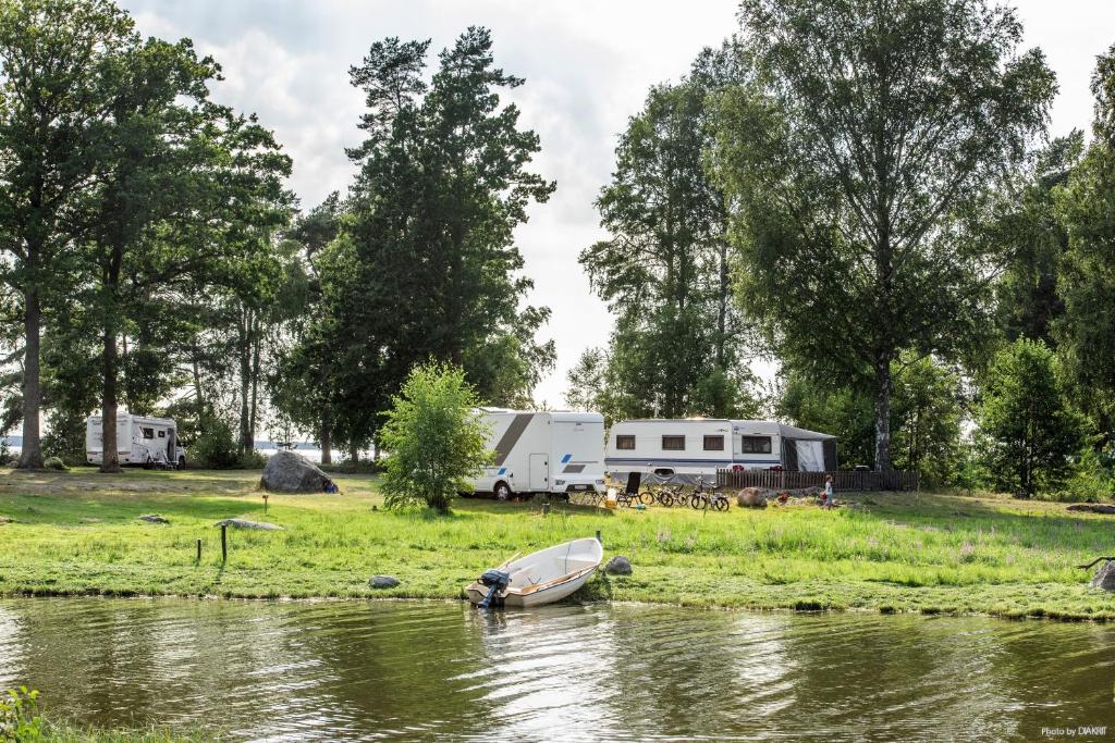 una barca seduta sull'erba vicino a un fiume di First Camp Ekudden-Mariestad a Mariestad