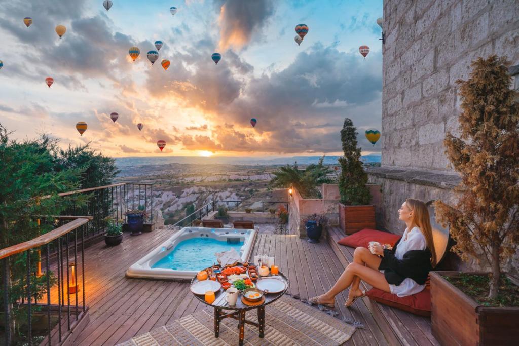 une femme assise sur une terrasse pour regarder des montgolfières dans l'établissement Taskonaklar, à Uçhisar