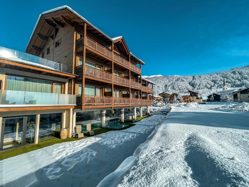 a snow covered road in front of a lodge at Francesin Active Hotel in Livigno