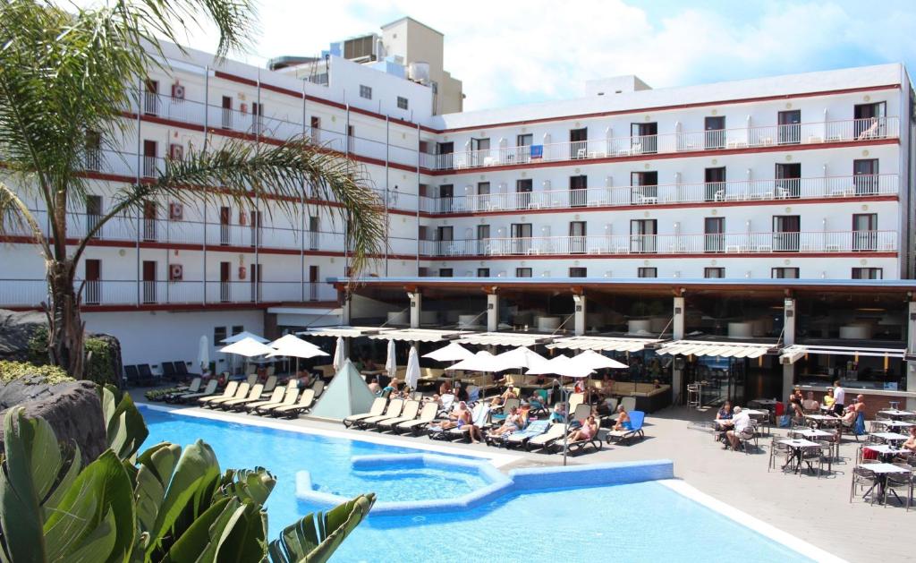 un hotel con gente sentada en sillas junto a una piscina en Hotel Papi en Malgrat de Mar