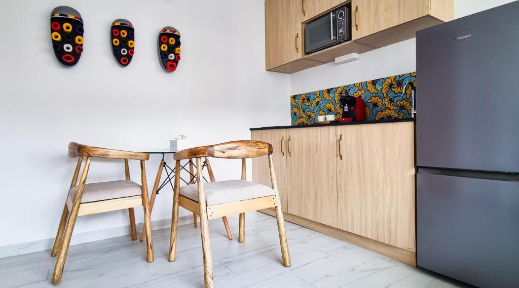 阿比讓的住宿－Cosy appart au cœur du Plateau，厨房配有两把椅子、一张桌子和一台冰箱
