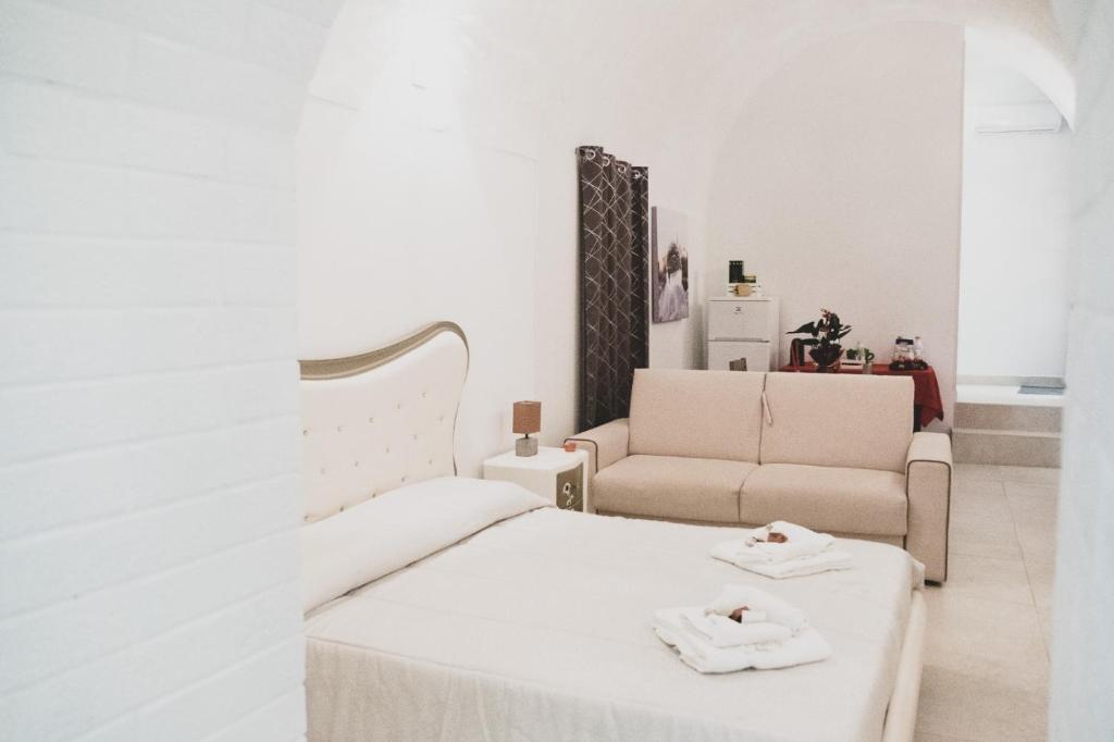 a white bedroom with a bed and a couch at Acasadifelice in Matera